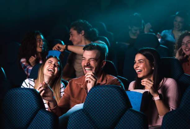 Group of cheerful people laughing while watching movie in cinema.
